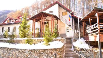 A building with a stone wall, wooden staircase, and a red roof.