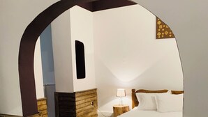 A bedroom with a wooden bed, a nightstand, a lamp, and a wooden archway.