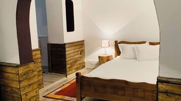 A bedroom with a wooden bed, a nightstand, a lamp, and a wooden archway.