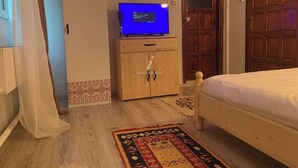 A bedroom with a wooden bed, a television on a wooden cabinet, and a patterned rug.