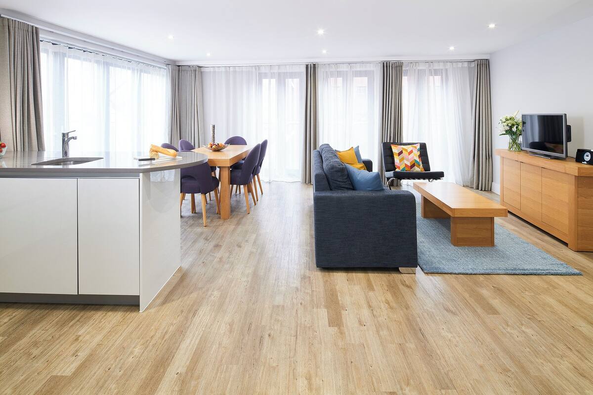 A modern living room with a sofa, coffee table, and dining area.