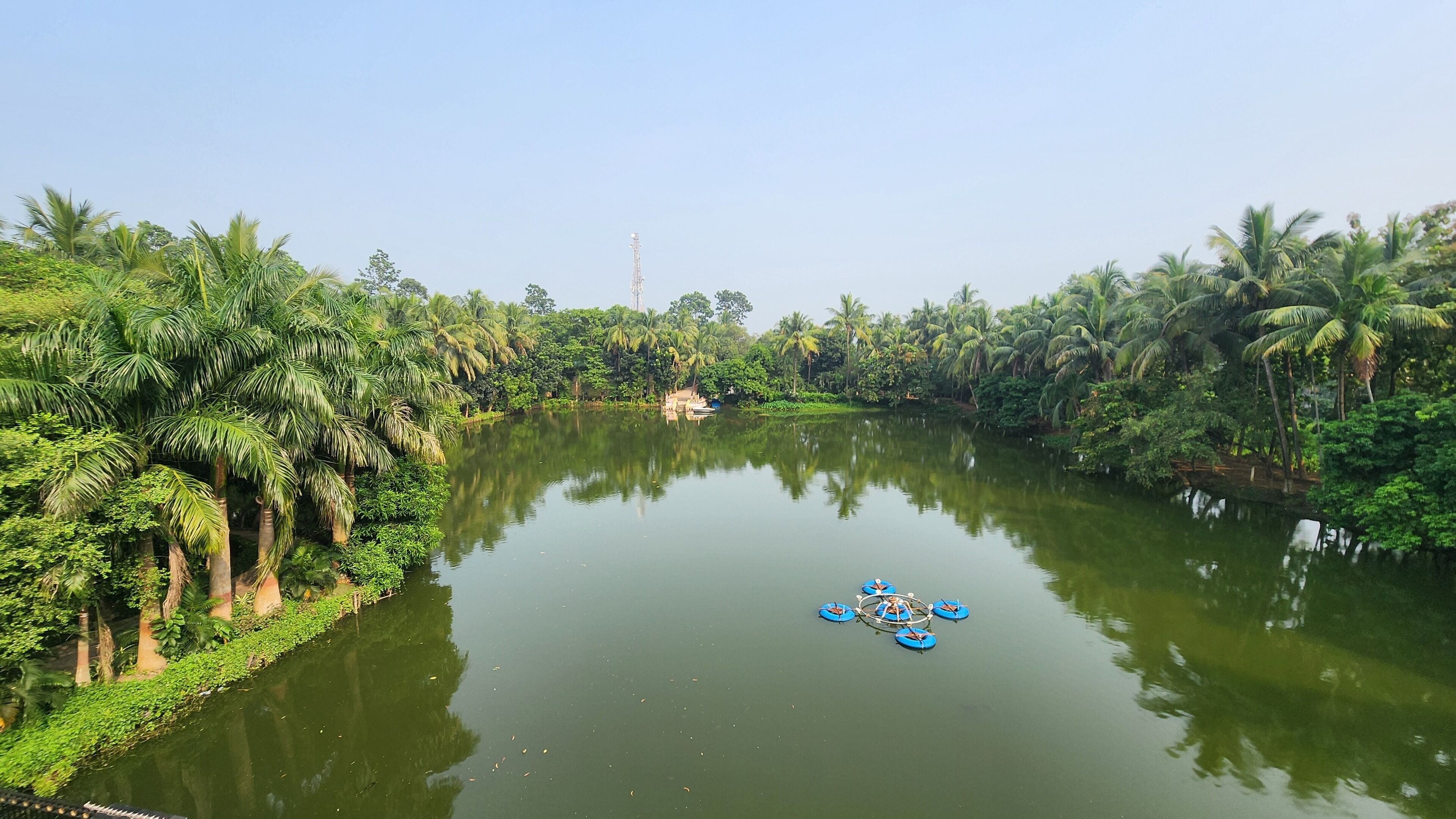 A calm river with dense greenery and a small boat.