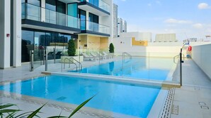 A modern hotel with a rooftop pool, glass railings, and a view of the city skyline. - Binghatti Lavender Residences- JVC (Dubai)