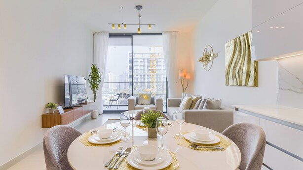 A modern dining area with a round table set for four, a sofa, and a TV in the background. - Binghatti Lavender Residences- JVC (Dubai)