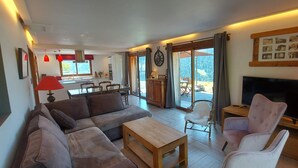 A living room with a sofa, chairs, a TV, and a dining area with a table and chairs. - Morzine: panoramic, south-facing, comfortable chalet (Morzine)