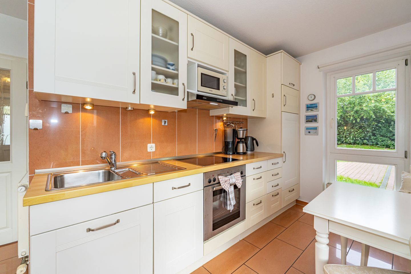 Eine moderne Küche mit weißen Schränken, einer Edelstahl-Spüle, einer Mikrowelle und einem Backofen.