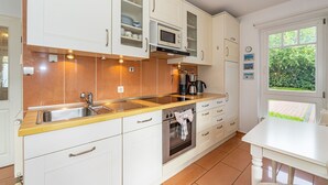 A modern kitchen with white cabinets, a stainless steel sink, a microwave, and an oven.