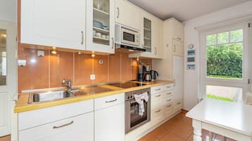 Eine moderne Küche mit weißen Schränken, einer Edelstahl-Spüle, einer Mikrowelle und einem Backofen.