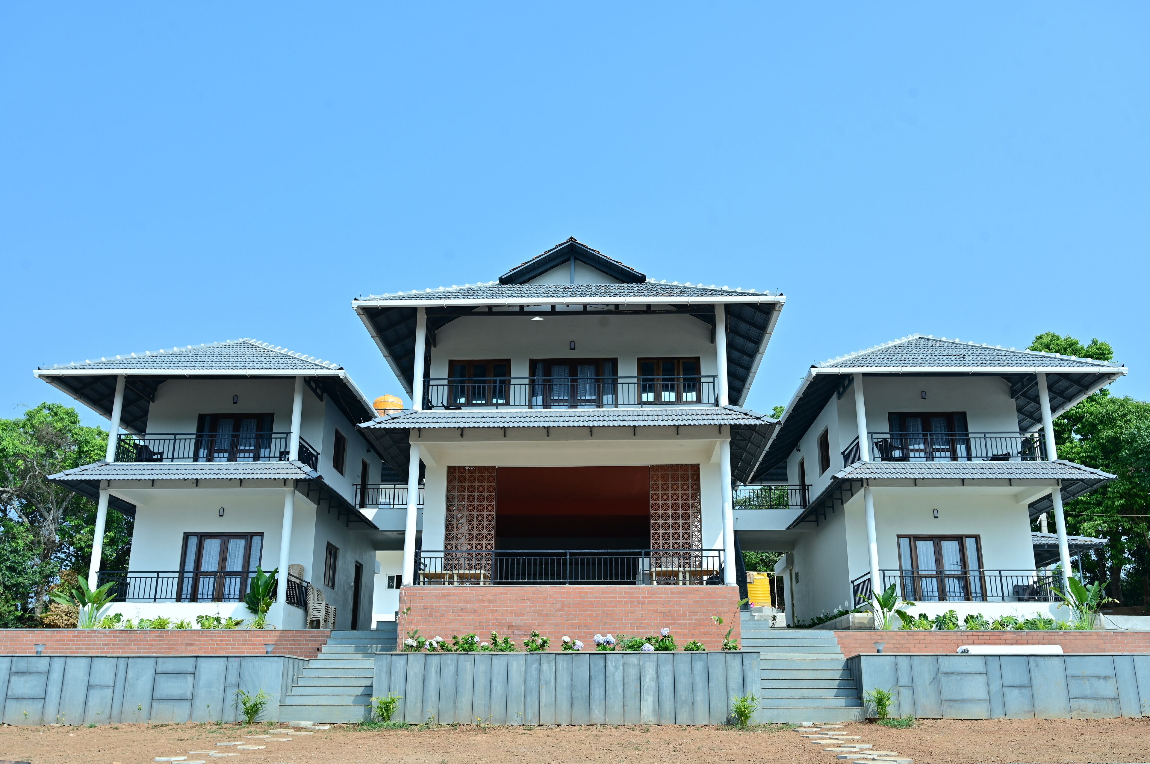 A two-story building with a central open porch, multiple balconies, and a brick base.