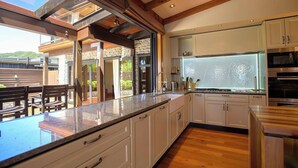 A modern kitchen with white cabinets, a granite countertop, and a large window. - Tata Tides Beach Front Retreat - Golden Bay at its finest (Tata Beach)