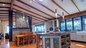 A spacious kitchen with wooden beams, a stone accent wall, and large windows. - Tata Tides Beach Front Retreat - Golden Bay at its finest (Tata Beach)