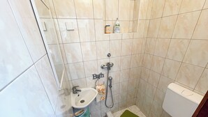 A small bathroom with a sink, toilet, and shower. - Studio Nadica (Šmrika)