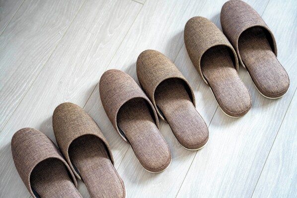 Un par de pantuflas marrones sobre un suelo de madera clara.