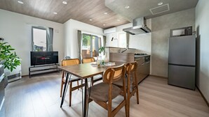 Une cuisine moderne avec un coin repas, des meubles en bois et un téléviseur à écran plat.