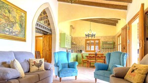 Uma sala de estar com sofá, poltronas e um espaço de jantar com mesa e cadeiras.