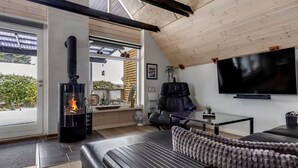 Un salon moderne avec une cheminée, un canapé, un téléviseur et une vue sur l’extérieur.