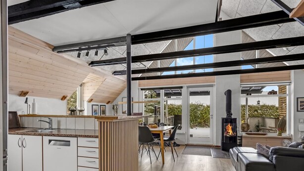 Une cuisine moderne dotée d’un îlot central, un coin repas avec une table et des chaises, une cheminée et un espace salon avec un canapé.