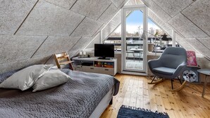 Une chambre aménagée en mezzanine comprenant un lit, un bureau, une chaise et un téléviseur.