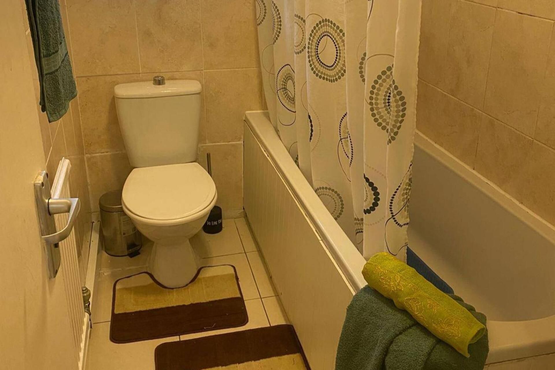 Une salle de bain avec des toilettes, un bidet et une baignoire. Il y a des serviettes sur le sol et une serviette accrochée au mur.