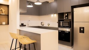 Une cuisine moderne avec un îlot central blanc, des appareils en acier inoxydable et deux chaises jaunes.