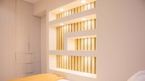 Une chambre à coucher comprenant un lit, une armoire et un éclairage intégré au mur.