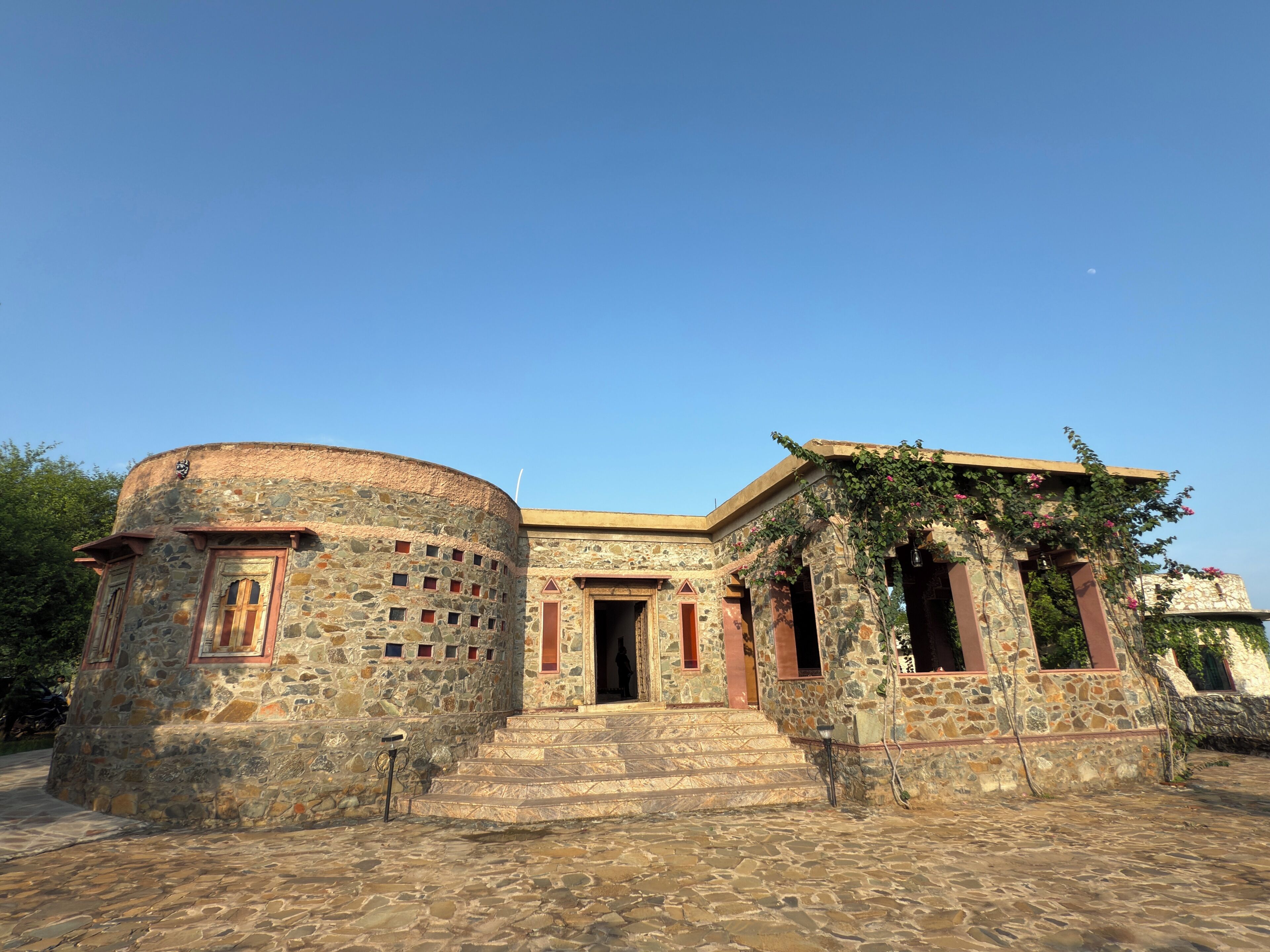 A stone building with a circular tower, a main entrance, and steps leading up to the door.