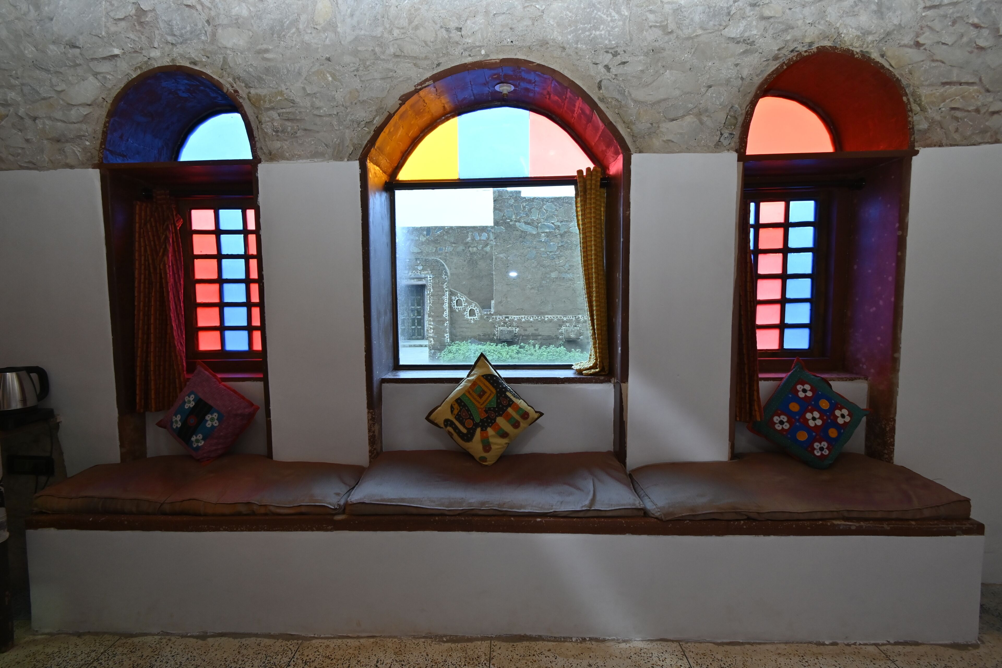 A bench with colorful stained glass windows and cushions.