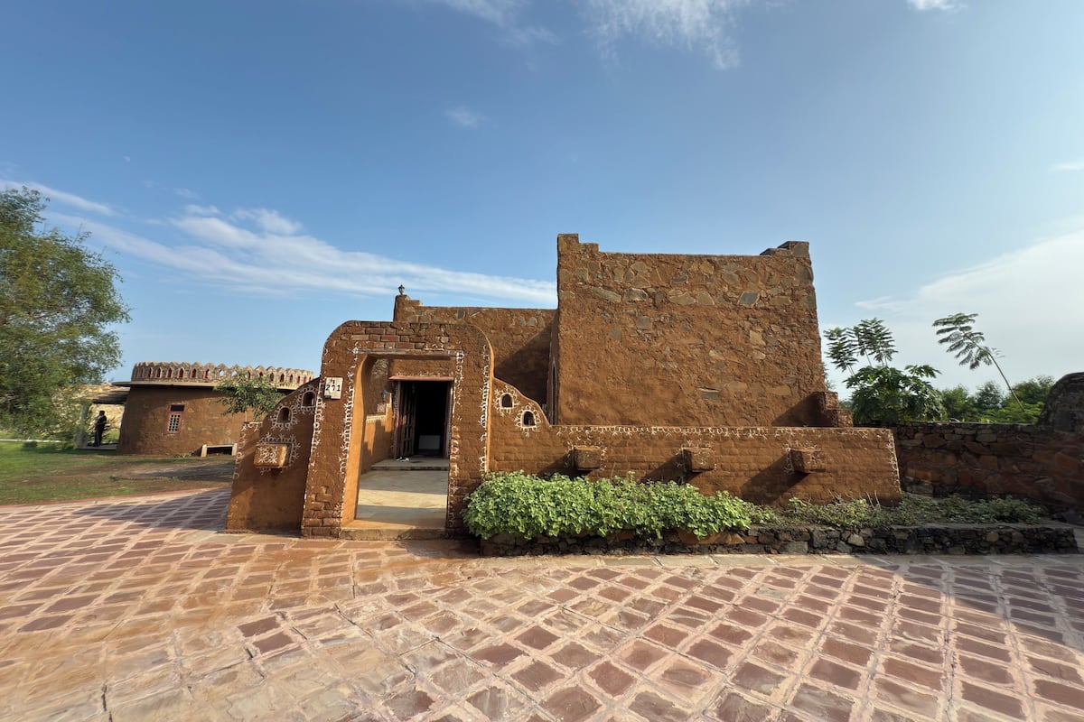 A historic building with a stone facade, a central doorway, and a paved courtyard.