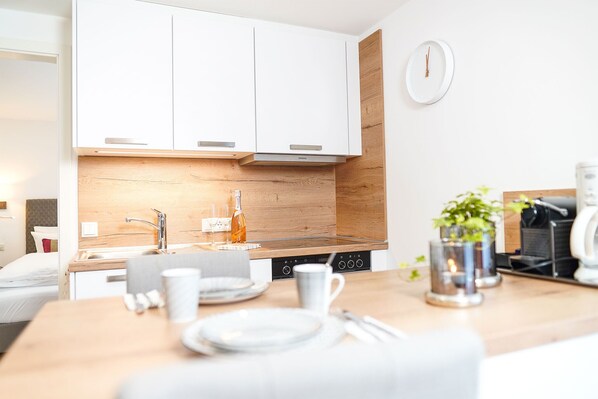 A modern kitchen with white cabinets, a wooden backsplash, and a built-in stove.