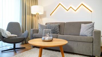 Ein modernes Wohnzimmer mit einem grauen Sofa, einem runden Couchtisch und einer Lampe.