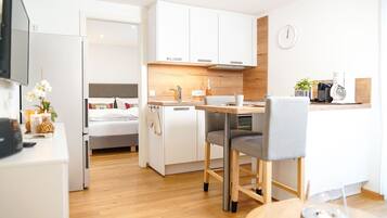 Eine moderne Küche mit weißen Schränken, einer Holzausziehtafel und einem Essbereich mit zwei Stühlen.