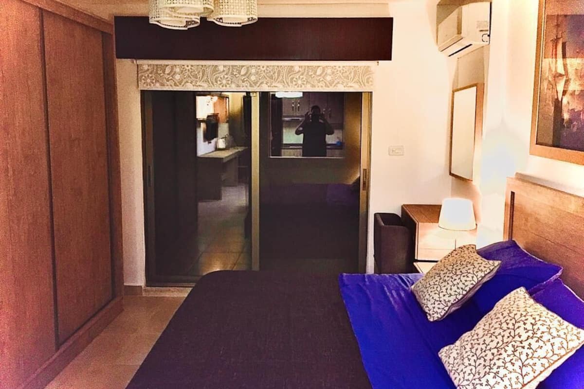 Ein Hotelzimmer mit einem Bett, einem Spiegel, einer Chandelierleuchtre und einer Tür zu einem Badezimmer.