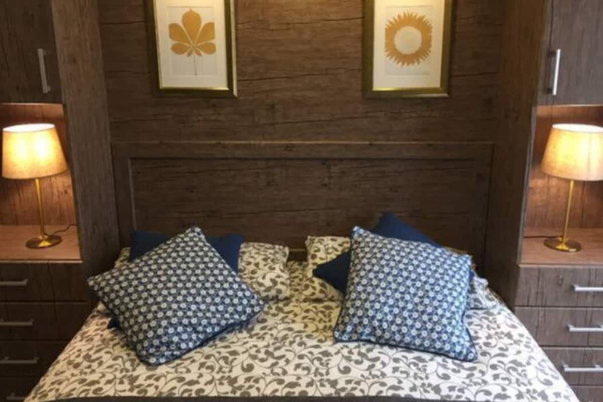 Ein Bett mit gemusterten Bettbezügen und zwei Kissen, begleitet von Nachttischen mit Lampen.