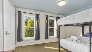 A bunk bed room with a window, curtains, and a ceiling light. - Rink Side Retreat (Grand Rapids)
