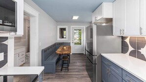 A modern kitchen with white cabinets, a built-in oven, and a wooden dining table with benches. - Rink Side Retreat (Grand Rapids)