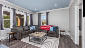 A modern living room with a sectional sofa, a coffee table, and a patterned rug. - Rink Side Retreat (Grand Rapids)