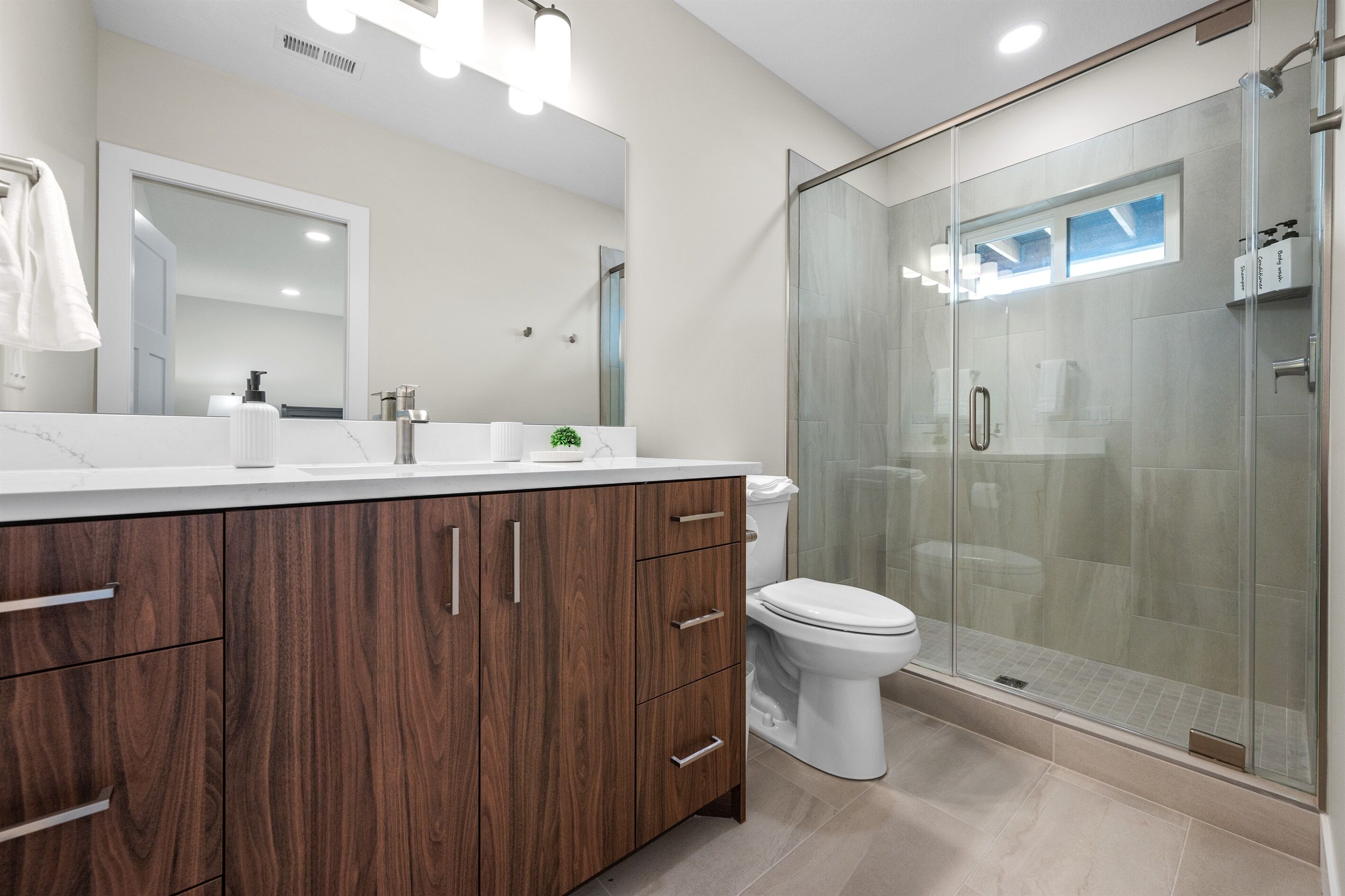 Une salle de bain moderne avec un meuble-lavabo en bois, une cabine de douche en verre et des toilettes.