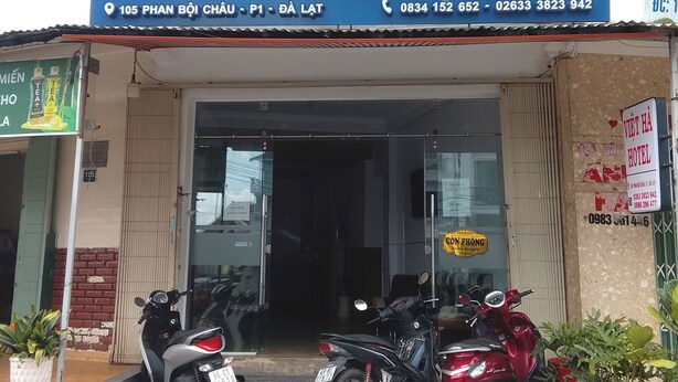 Um hotel chamado "Viet Ha" com uma placa azul, duas motocicletas estacionadas e uma entrada visível.