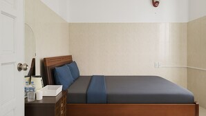 Quarto bem arrumado com cama, mesa de cabeceira e luminária na parede.