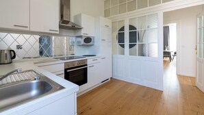 Une cuisine moderne avec des meubles blancs, une hotte en acier inoxydable, un four à micro-ondes et un four encastré.