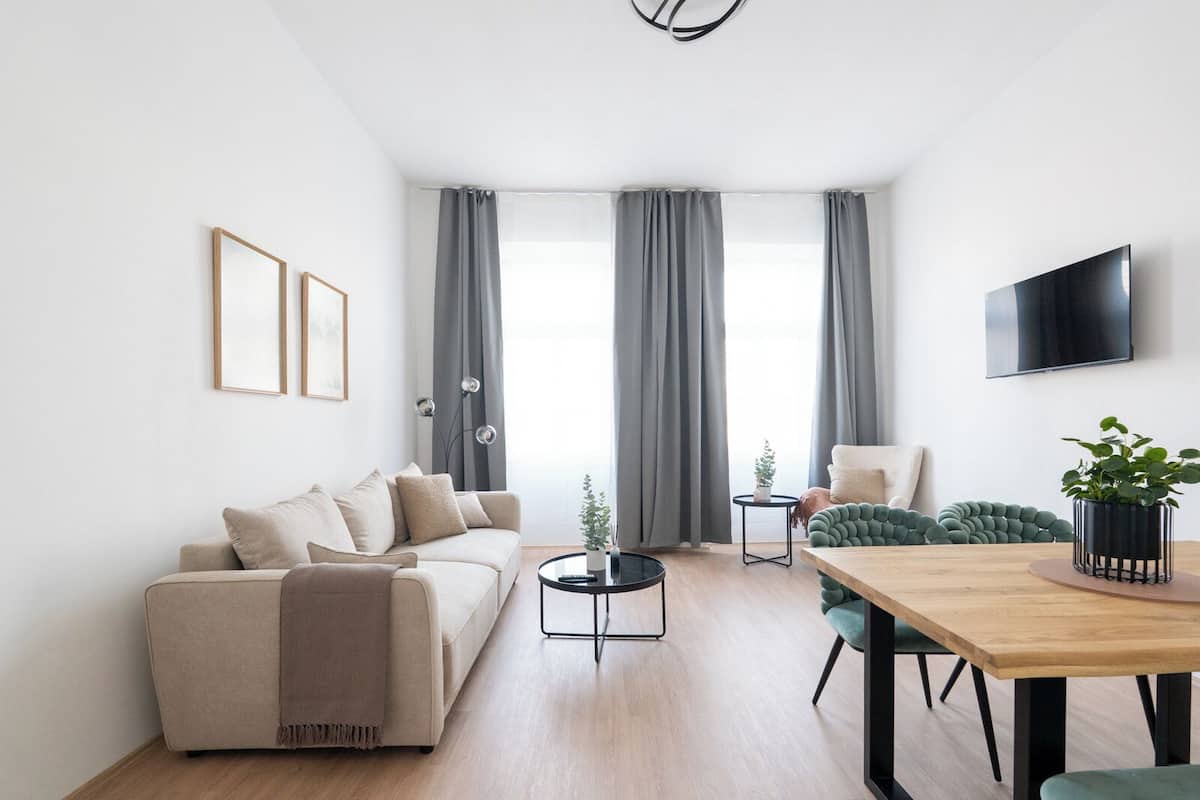 Ein modernes Wohnzimmer mit einer Couch, einem Esstisch, einem Fernseher und einer Pflanze.