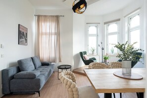 A modern living room with a grey sofa, a round wooden table, and a green armchair.