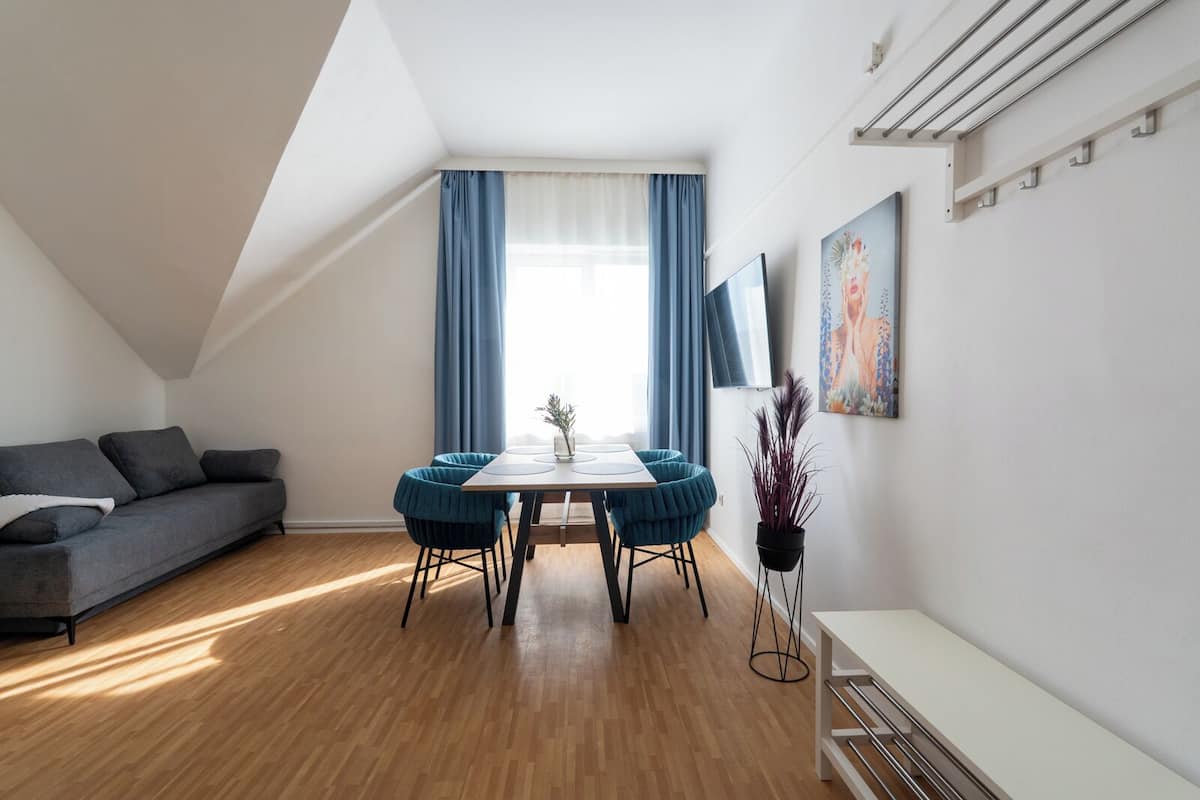 Ein modernes Loft-Apartment mit Essbereich, einer Couch und einem großen Fenster mit Vorhängen.