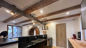 A modern kitchen with wooden beams, a black countertop, and a wooden door.