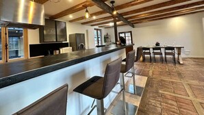 A modern kitchen with a bar area, wooden beams, and a dining space with a herringbone floor pattern.