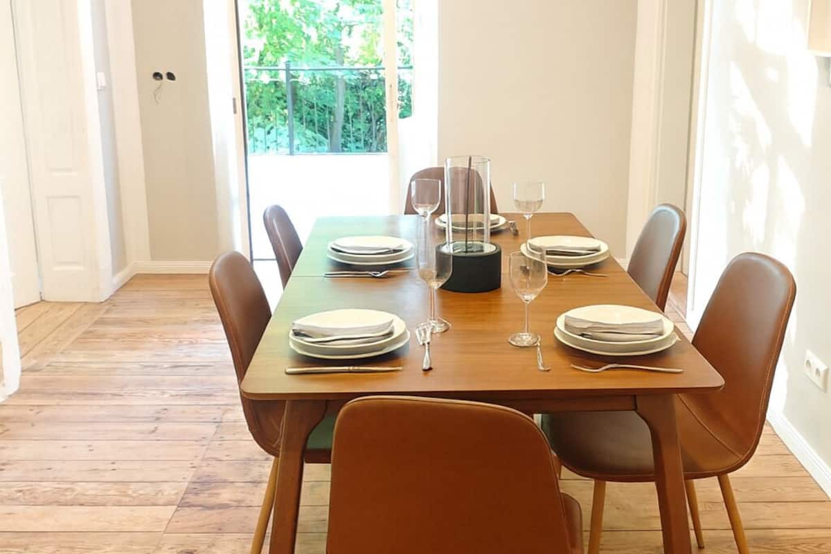 Comedor con una mesa de madera dispuesta para cuatro personas, rodeada de cuatro sillas.