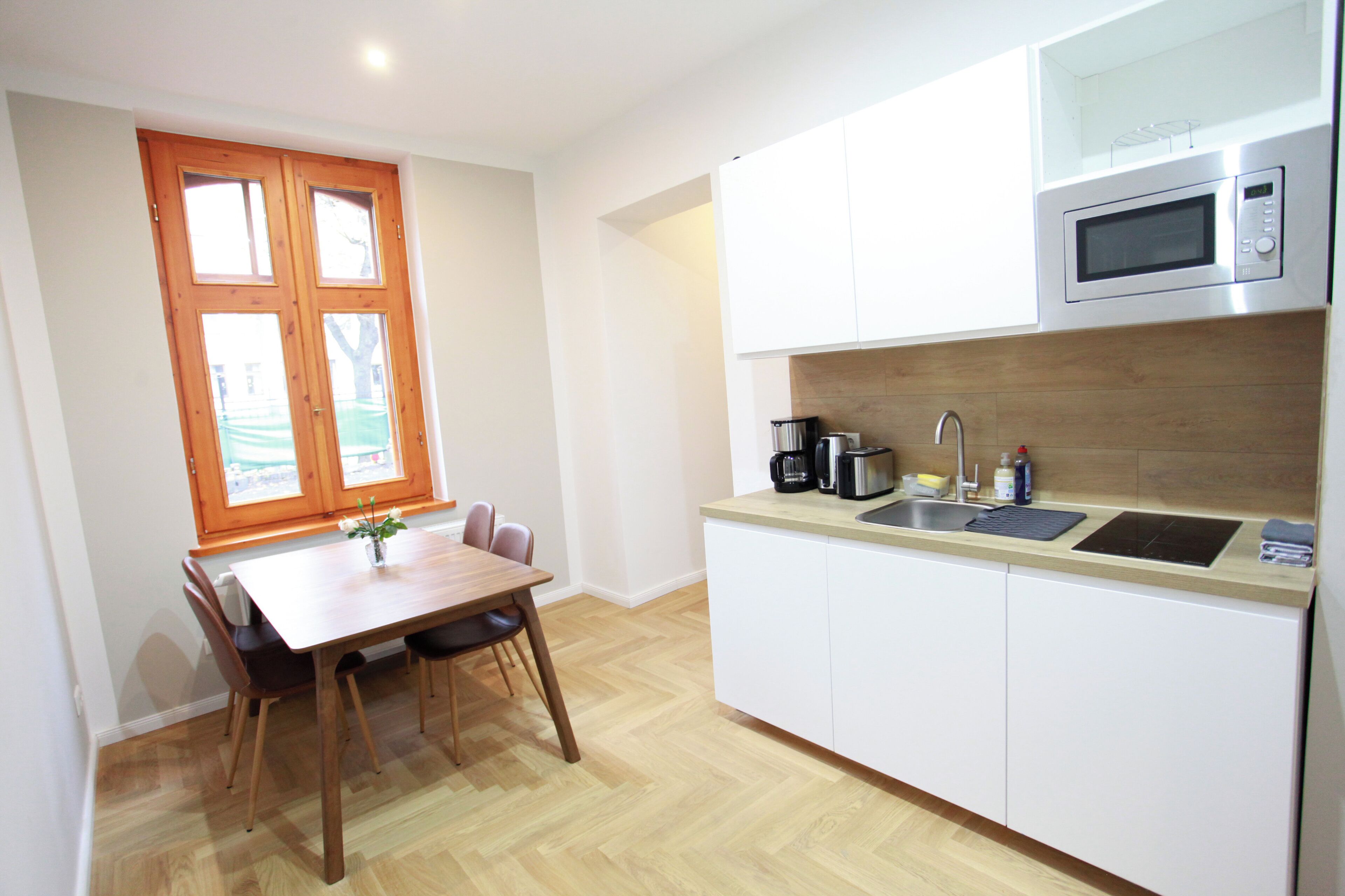 Una cocina moderna con armarios blancos, una mesa de comedor de madera y un ventanal con vistas.