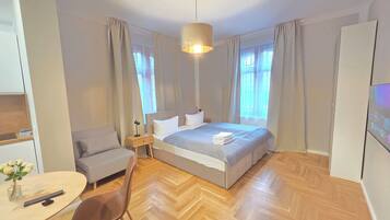 Une chambre d’hôtel moderne avec un grand lit, un bureau avec une chaise, une petite table ornée d’un vase de fleurs et un téléviseur.