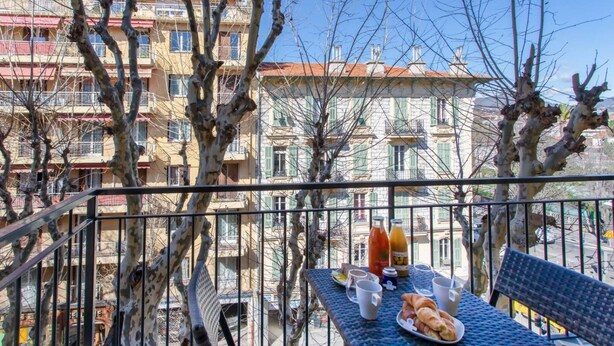 Ein Balkon mit Tisch für zwei Personen, gedeckt mit Croissants und einer Orangensaftflasche.