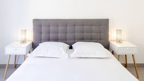 Ein Bett mit einem gebuschten Kopfteil, zwei Nachttische und zwei Lampen.